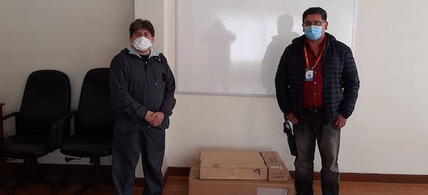 Deux hommes avec des masques debout à côté d'emballages en carton